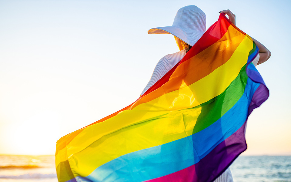 Frau mit Regenbogenflagge am Meer auf Gran Canaria